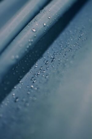 Close-up image of raindrops on a textured blue surface, creating a serene and abstract composition.